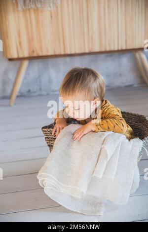 Hübsches blondes Baby, das in einem Wäschekorb sitzt Stockfoto