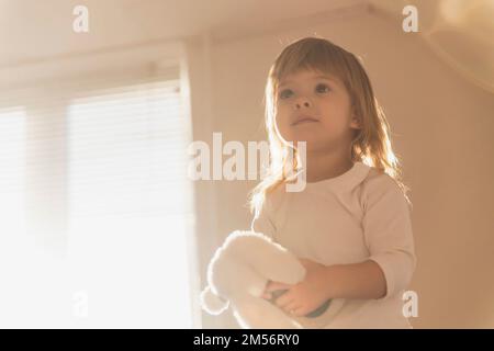 Charmantes blondes Baby mit einem Spielzeug am Morgen Stockfoto