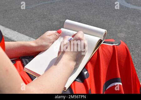 Eine Nahaufnahme von Frauenhänden, die auf ein Notizbuch schreiben Stockfoto