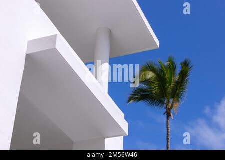 Abstrakter minimaler architektonischer Hintergrund mit weißem Betongebäude außen und Palme unter blauem Himmel an einem sonnigen Tag Stockfoto