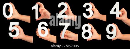 Kinderhände halten Zahlen. Ein Satz weißer Zahlen in der Hand auf schwarzem isoliertem Hintergrund. Null, eins, zwei, drei, vier, Fünf, sechs, sieben, acht Stockfoto