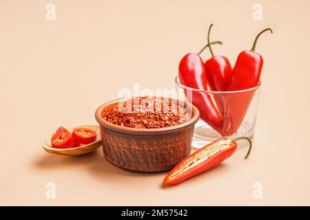 Schüssel mit Chipotle Chili-Flocken und frischen Jalapeno-Paprika auf farbigem Hintergrund Stockfoto