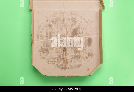 Leere fettige Pizza-Box auf grünem Hintergrund Stockfoto