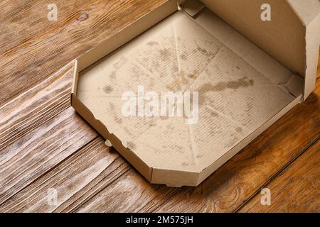 Leere fettige Pizzaschachtel auf Holzhintergrund Stockfoto