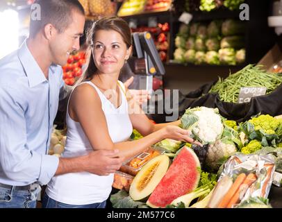 Fröhliches junges Paar, das frisches Obst und Gemüse auswählt Stockfoto