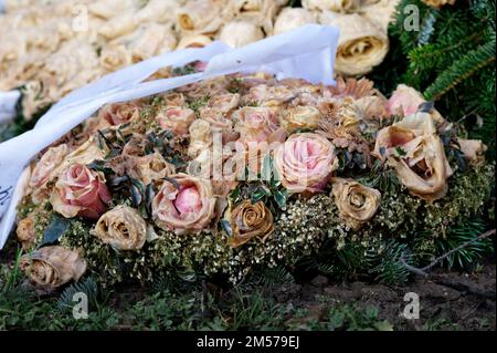 Pastellfarbene Blumendekoration mit Rosen auf einem Grab Stockfoto