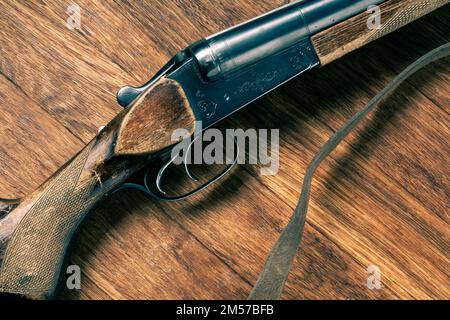 Antike 16-Gauge-Schrotflinte mit glatter Bohrung auf Holztisch. Stockfoto