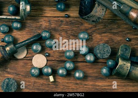 Antike, glatte Schrotflinte mit 16 mm Durchmesser und Messingkoffern, Zubehör zum Nachladen der Kartusche auf dem Holztisch. Stockfoto