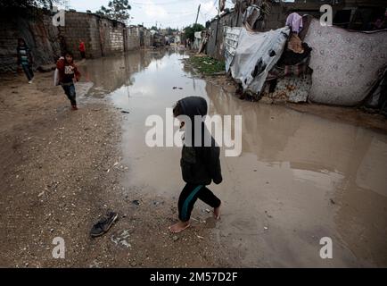 Gaza, Palästina. 26. Dezember 2022. Ein palästinensisches Mädchen läuft auf einer mit Regenwasser überfluteten Straße in Khan Yunis, im südlichen Gazastreifen. Kredit: SOPA Images Limited/Alamy Live News Stockfoto