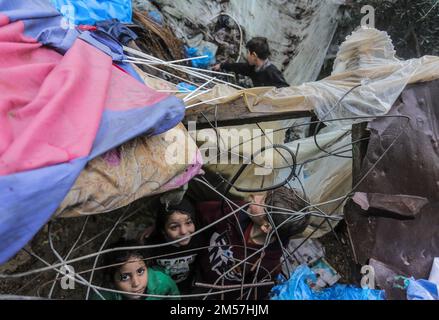 Gaza-Stadt, Palästina. 26. Dezember 2022. Palästinensische Flüchtlingskinder spielen während des kalten Wetters im nördlichen Gazastreifen in ihrer vorübergehenden Heimat. Die Palästinenser in den Slums von Beit Lahiya im nördlichen Gazastreifen sehen sich angesichts des kalten Wetters schwierigen Bedingungen gegenüber. Kredit: SOPA Images Limited/Alamy Live News Stockfoto