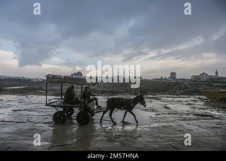 Gaza-Stadt, Palästina. 26. Dezember 2022. Palästinensische Flüchtlinge reiten auf einem Wagen während des Regens im nördlichen Gazastreifen. Die Palästinenser in den Slums von Beit Lahiya im nördlichen Gazastreifen sehen sich angesichts des kalten Wetters schwierigen Bedingungen gegenüber. (Foto: Mahmoud Issa/SOPA Images/Sipa USA) Guthaben: SIPA USA/Alamy Live News Stockfoto