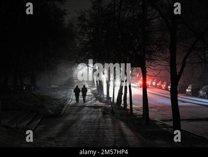 Kiew, Ukraine. 26. Dezember 2022. Menschen gehen während eines schweren Schneefalls in Kiew eine dunkle Straße entlang. Die russische Armee führte massive Raketen- und Kamikaze-Drohnenangriffe auf die ukrainische Energieinfrastruktur durch. Nach schweren Schäden am Stromnetz in vielen Städten der Ukraine führte die National Power Company Ukrenergo Notfall- und stündliche Stromausfälle ein. Kredit: SOPA Images Limited/Alamy Live News Stockfoto