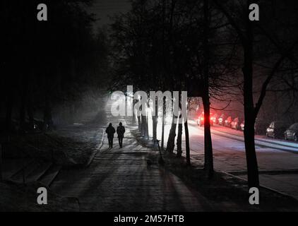 Kiew, Ukraine. 26. Dezember 2022. Menschen gehen während eines schweren Schneefalls in Kiew eine dunkle Straße entlang. Die russische Armee führte massive Raketen- und Kamikaze-Drohnenangriffe auf die ukrainische Energieinfrastruktur durch. Nach schweren Schäden am Stromnetz in vielen Städten der Ukraine führte die National Power Company Ukrenergo Notfall- und stündliche Stromausfälle ein. (Foto: Sergei Chuzavkov/SOPPA Images/Sipa USA) Guthaben: SIPA USA/Alamy Live News Stockfoto