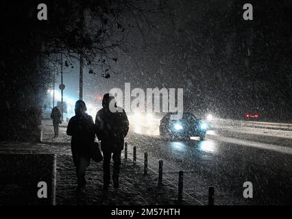 Kiew, Ukraine. 26. Dezember 2022. Menschen gehen während eines schweren Schneefalls in Kiew eine dunkle Straße entlang. Die russische Armee führte massive Raketen- und Kamikaze-Drohnenangriffe auf die ukrainische Energieinfrastruktur durch. Nach schweren Schäden am Stromnetz in vielen Städten der Ukraine führte die National Power Company Ukrenergo Notfall- und stündliche Stromausfälle ein. (Foto: Sergei Chuzavkov/SOPPA Images/Sipa USA) Guthaben: SIPA USA/Alamy Live News Stockfoto