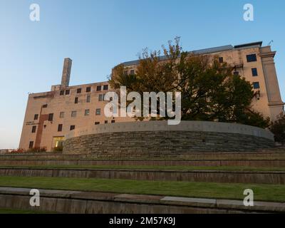 Blick von außen auf das Oklahoma City National Memorial Museum, den Survivor Tree mit Herbstlaub und die Steinmauer. Stockfoto