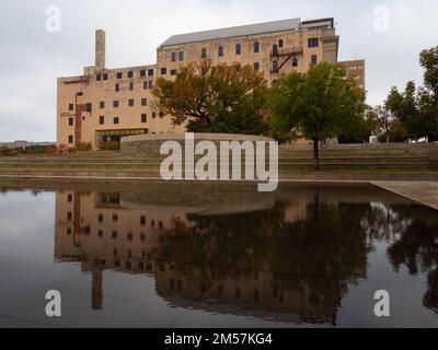 Das Oklahoma City National Memorial Museum und der Survivor Tree mit Herbstlaub. Eine Reflexion des Gebäudes und des Baumes ist im Pool zu sehen. Stockfoto