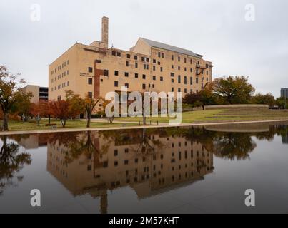 Das Oklahoma City National Memorial Museum, der Survivor Tree und Laubbäume mit Herbstlaub spiegeln sich im reflektierenden Pool in Oklahoma City, OK, wider Stockfoto