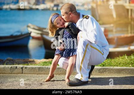 Du wirst immer mein kleines Mädchen sein. Porträt eines Vaters in Navy Uniform, der mit seinem kleinen Mädchen auf dem Dock posiert. Stockfoto