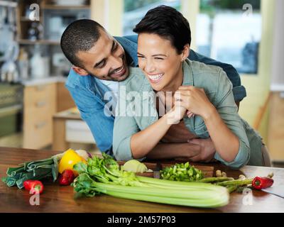 Was kocht, sieht gut aus. Ein liebevolles junges Paar, das zusammen in der Küche ein Essen zubereitet. Stockfoto