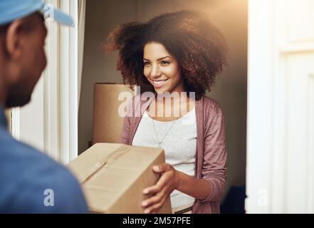 Direkt zur Tür. Ein Postangestellter, der einem jungen weiblichen Kunden ein Paket liefert. Stockfoto