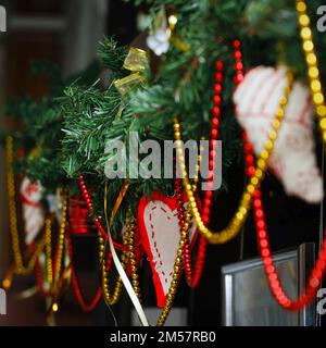 Weihnachtsgirlande mit Weihnachtsbaumzweigen und Spielzeug im Zimmer. Selektiver Fokus Stockfoto