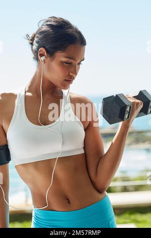 Du bist der Schneider deines eigenen Körpers. Eine junge Frau, die beim Training Kurzhanteln benutzt. Stockfoto