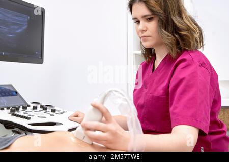 Eine Ärztin, die einen Ultraschall am Kniegelenk einer Patientin in einem medizinischen Zentrum macht. Medizin und Gesundheitskonzept. Stockfoto