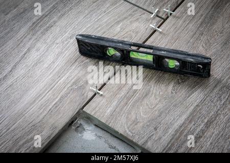 Schwarze Wasserwaage auf Fliesen. Fliesenarbeiten, Renovierung und Bau. Stockfoto