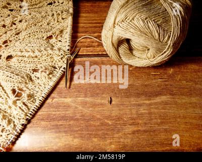 Durchbrochene Tischdecke beim Stricken. Stricknadeln, Schlaufen auf Stricknadeln, Strickstoff, Fadenknäuel, grobe Baumwolle und Leinen Stockfoto