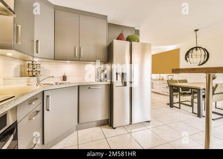 Küche und Essbereich in einem kleinen Apartment mit Edelstahlgeräten auf der Theke, Spüle, Kühlschrank und Geschirrspüler Stockfoto