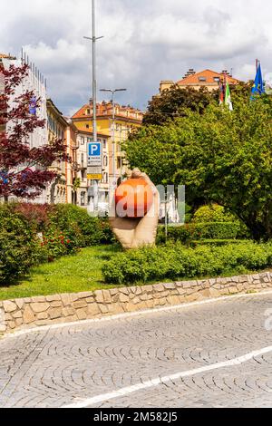 Hand mit einem orangefarbenen Denkmal, das der Schlacht der Orangen gewidmet ist, der Tradition des Karnevals in Ivrea, Piemont, Italien Stockfoto