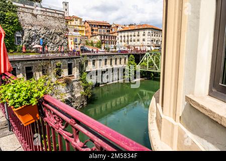 Dora Baltea Fluss von einer roten Brücke aus gesehen, mit einem alten verlassenen Hotel in Ivrea, Stadt berühmt für den Karneval, Piemont Region, Italien Stockfoto