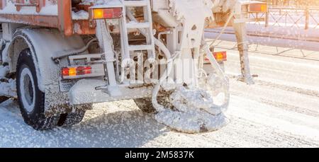 Schneepflug auf der Highway Salting Road. Orangefarbene LKW-Enteisungsstraße. Wartung Winterstreuwagen Stockfoto