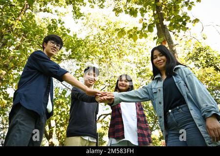 Bild von jungen Menschen, die gemeinsam feiern, während sie ihre Hände im Freien stapeln. Beziehungsjugend und Gemeinschaftskonzept Stockfoto