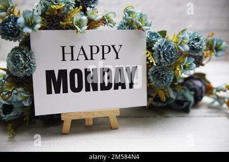 Happy Monday Text auf hölzerner Staffelei, die auf weißen Ziegelwänden und Holzhintergrund steht Stockfoto