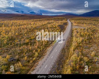 Luftaufnahmen von Car Camping Caravan, die auf der Straße am See tief im schwedischen Lappland unterwegs sind. Sonniger Tag und Herbstfarben im Abisko-Nationalpark Schweden Stockfoto