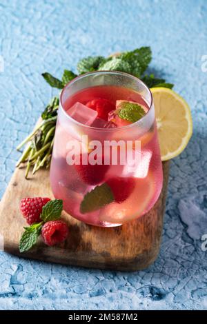 Himbeerlimonade Getränk in Glas auf blauem Hintergrund Stockfoto