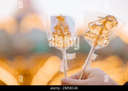 Hand hält Weihnachten goldene Lutscher, Süßigkeiten auf dem Stock. Hochwertiges Foto Stockfoto