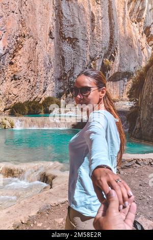 Eine junge Frau, die den Mann an der Hand hält, während sie ihn auf die Natur führt. Konzept von Reisen und Liebe Stockfoto