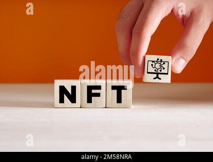 NFT-Konzept für nicht fungible Token. Die Hand legt die Holzwürfel mit der Abkürzung NFT und dem Symbol. Stockfoto