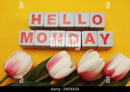 Montags ein hölzernes Alphabet mit Tulpenblüten auf gelbem Hintergrund Stockfoto