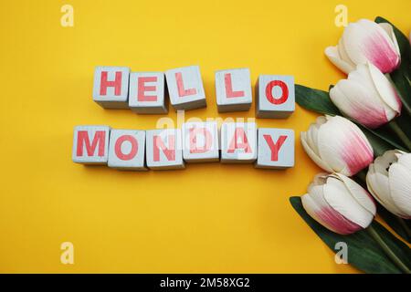 Hallo Montag, hölzernes Alphabet mit Tulpenblume auf gelbem Hintergrund Stockfoto