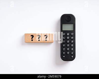 Konzept für Kundenhilfe und -Support. Fragezeichen auf Holzblock mit drahtlosem Telefon. Stockfoto