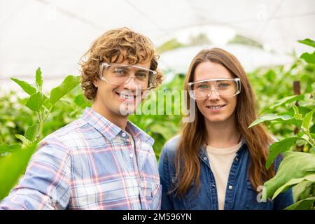 Ein glückliches Paar von Landwirtschaftlern, die sich im Gewächshaus fotografieren Stockfoto