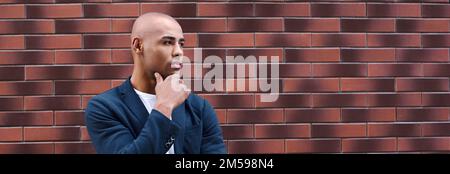 Kreatives Denken. Der junge Mann, der an der Wand steht, ist aufmerksam Stockfoto
