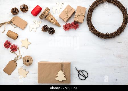 Weihnachtsgeschenk, Geschenke in braunen Kisten, Kiefernzapfen, Scheren, Holzschmuck auf weißem Holztisch Stockfoto
