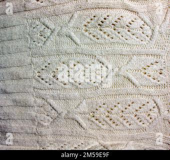 Die Konsistenz eines großen Strickpulvers oder Schals. Gestrickter Hintergrund mit Reliefmuster. Wollhandstricken oder maschinelles Stricken. Stoffhintergrund. Stockfoto
