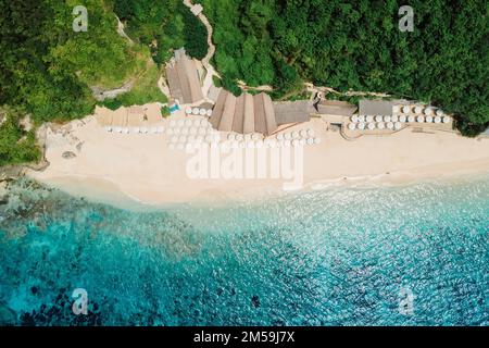 Luftblick auf den blauen Ozean und tropischen Strand mit Sonnenschirmen auf Bali Stockfoto