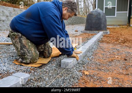 Professioneller Deckenfertiger legt Steine für den Weg auf dem Hof des Meisters. Stockfoto