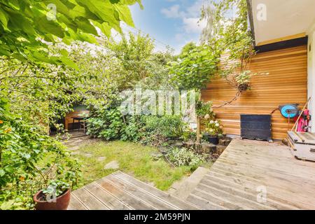 Ein Außenbereich mit Holzdielen und grünen Pflanzen auf dem Boden, umgeben von üppiger Vegetation im Hintergrund Stockfoto